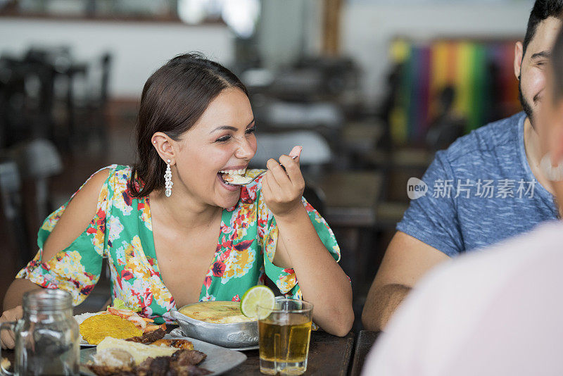 一位拉丁妇女在吃到她的菜时做了一个开心的脸，典型的哥伦比亚食物阿马里洛la Monseñor